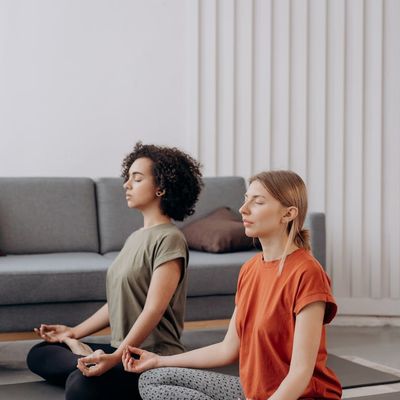 Woman meditating peacefully in a bright living room.
